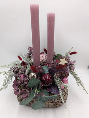 Adventsgesteck von vorn: Korb mit Eukalyptus, Holzstern, roségoldenen Kugeln und zwei rosa Kerzen
