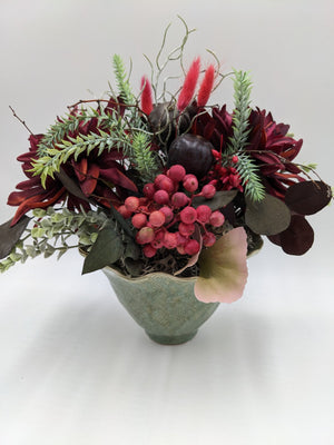 Herbstgesteck mit dunkelroten Dahlien, Feigen, rosaroten Beeren und Gräsern in grüner Keramikschale