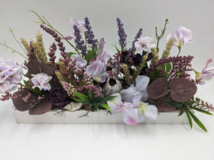 Längliches Sommergesteck in weißem Holztablett mit fliederfarbenen Wicken, Lavendel, Ähren und Muscheln