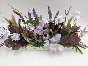 Sommergesteck aus der Nähe: helle Hyazinthen, dunkelviolette Rose, Lavendelrispen und braunviolette Blätter