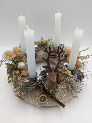 Adventskranz von oben: Wollring in Creme mit Hirsch, Orangenscheibe, Beeren, Trockenblüten und vier weißen Stabkerzen