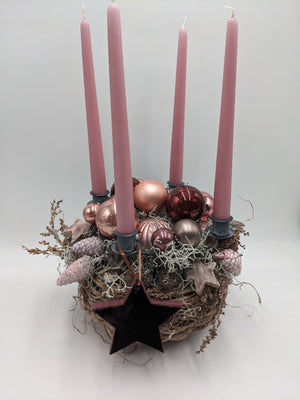Adventsgesteck im Geästnest mit vier rosa Stabkerzen, rosé und roten Glaskugeln, Zapfen und Samtstern