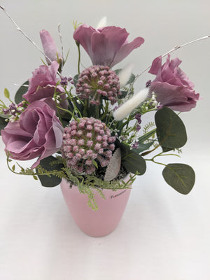Sommergesteck von oben: altrosa Rosen, Blütenkugeln, weiße Beeren und helle Muschel über grauem Moos