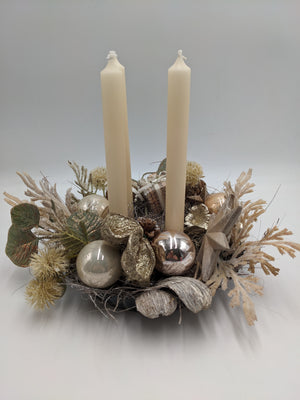 Adventsgesteck in Schale mit zwei cremefarbenen Stabkerzen, Glaskugeln, Stern und hellen Gräsern