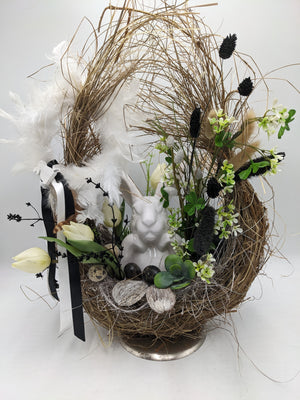 Ostergesteck im hohen Zweignest mit weißem Keramikhasen, cremefarbenen Tulpen, Federn und schwarz-weißer Schleife