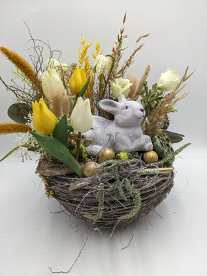 Ostergesteck im Weidennest mit gelben und weißen Tulpen, Schachbrettblumen, Gräsern und grauem Hasen