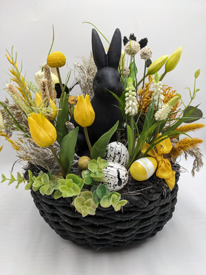 Ostergesteck im schwarzen Korb mit schwarzem Hasen, gelben Tulpen, Craspedia, weißen Hyazinthen und Ostereiern