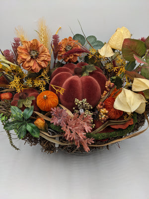 Herbstgesteck aus der Nähe: Samtkürbis in Bordeaux, kleine orange Kürbisse, Beerendolden und creme Physalis