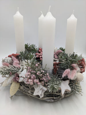 Adventskranz von vorn: weiße Kerzen, Birkenrinde-Sterne, helle Kugeln und rosa Gräser auf hellem Geflecht