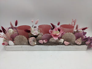 Längliches Sommergesteck im weißen Holztablett mit drei rosa Teelichtgläsern, Hortensien, Gräsern und Muscheln