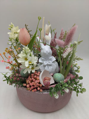 Ostergesteck von vorn: Hase, Eierschale mit Schnecken, türkises Ei und rosa Beeren in flacher Schale