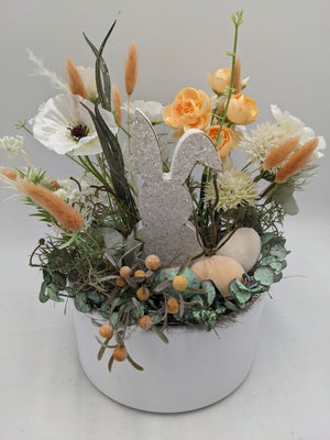 Frühlingsgesteck von vorn: Holzhase, Lagurus-Gräser, Eukalyptus und drei Eier in Creme, Apricot und Mint