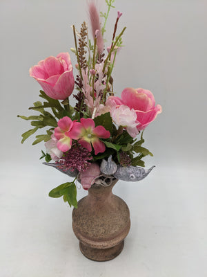 Rosa Frühlingsgesteck in rustikaler Vase mit Mohn, zarten Zweigen und grauen Trockenfrüchten am Rand