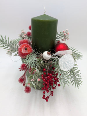 Wintergesteck von oben: grüne Kerze, rote Weihnachtskugel, zuckrige Äpfel, Beerenrispe und weiße Blätter