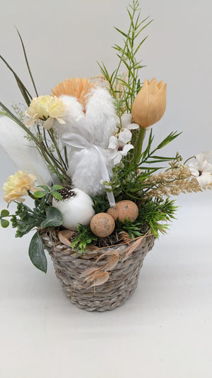 Frühlingsgesteck in Apricot und Weiß mit Hase, Gerbera, Ähren, Gräsern und Terrakotta-Eiern auf Moos