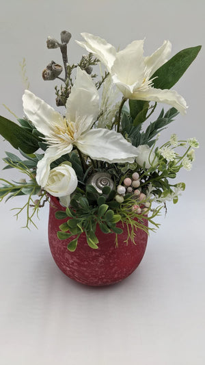 Frühlingsgesteck von vorn: weiße Clematis, cremeweiße Ranunkel, rosa Beeren und silbernes Schneckenhaus