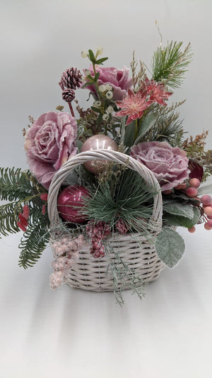 Tischgesteck im Korbhenkel-Körbchen mit rosa Rosen, beerenroter Kugel, Kiefernzweigen und weißen Beeren