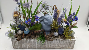 Ostergesteck im grau gekalkten Holzkasten mit graublauem Keramikhasen, blauen Veilchen, Lavendel und gesprenkelten Eiern