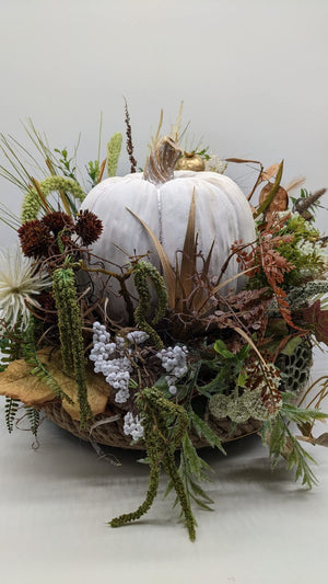 Herbstgesteck mit weißem Kürbis, weißen Beeren, grünem Amaranth und dunkelroten Disteln in flacher Naturschale