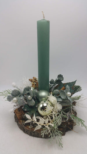 Weihnachtsgesteck auf Holzscheibe mit hoher grüner Kerze, silbernen Glitzerblättern, Kugeln und weißen Perlen