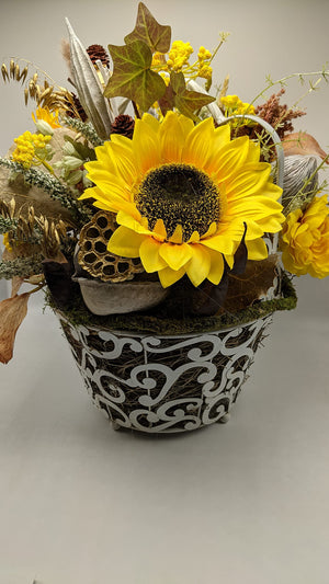 Nahaufnahme einer gelben Sonnenblume mit goldener Lotusschale über dem weißen Metallkorb mit Ornamenten