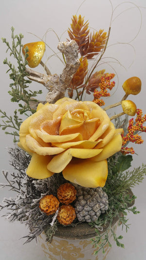 Nahaufnahme der gelb-orangen Rose mit Mini-Zapfen, grauem Zapfen, Beerenrispen und beschneiten Zweigen