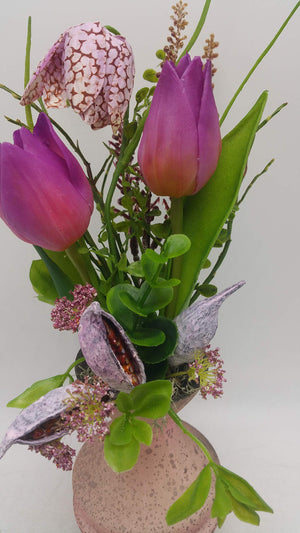 Nahaufnahme der lila Tulpen, der gemusterten Schachbrettblume und der aufgeplatzten Schoten mit grünen Blättern