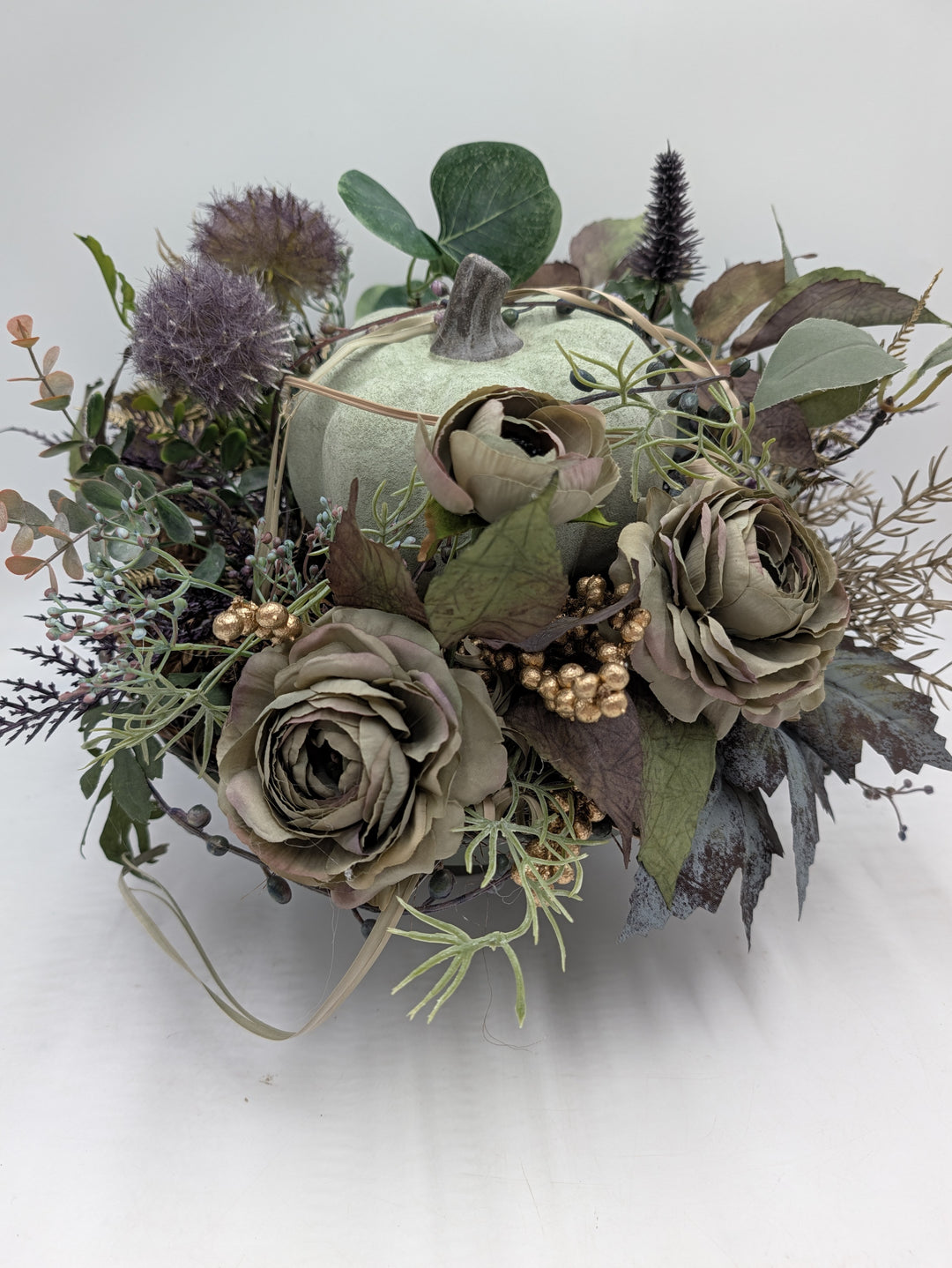Herbstgesteck von oben: Kürbis in der Mitte, drei Rosen, Eukalyptus und braune Herbstblätter