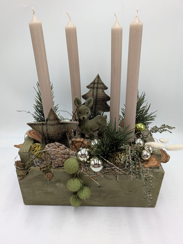 Adventsgesteck von vorn: Holzkasten grün, vier Kerzen, Reh und Tannenbaum aus Filz, Kiefernzweige und Gräser