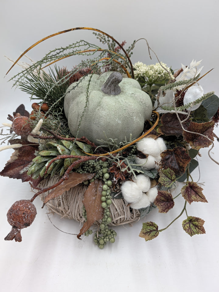 Seitliche Ansicht des Herbstgestecks: grüner Kürbis, Baumwolle, Hagebutten, Gräser und Eukalyptus in Grün und Braun