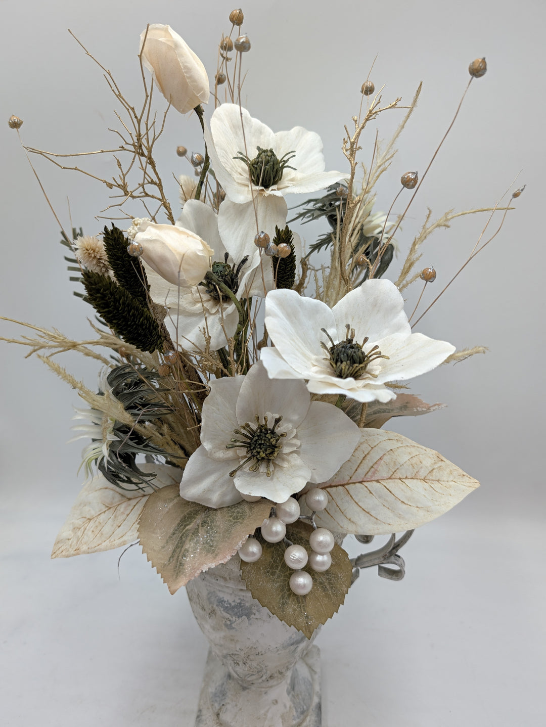 Nahaufnahme der Christrosen mit grünen Staubgefäßen, cremefarbenen Blättern und weißer Perlentraube
