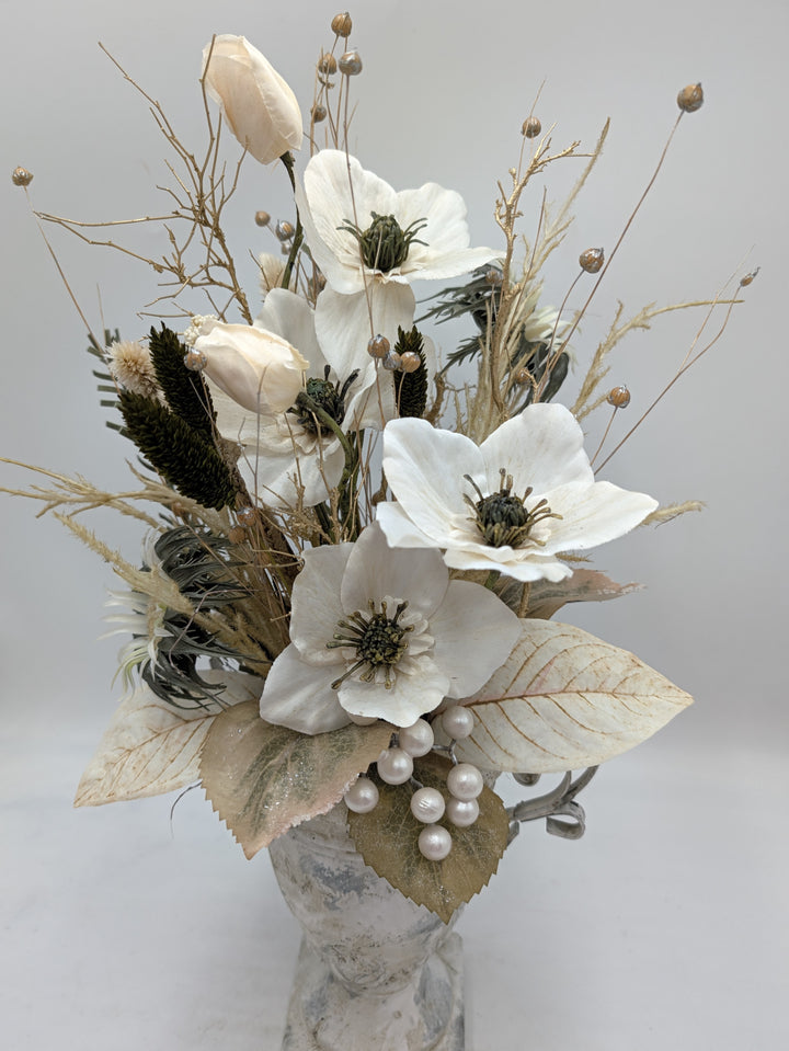 Nahaufnahme der Christrosen mit grünen Staubgefäßen, cremefarbenen Blättern und weißer Perlentraube