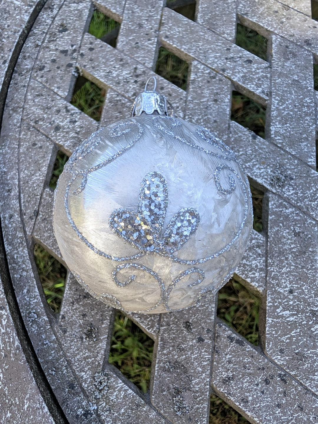Weihnachtskugel in Silber und Weiß mit Aufhängekappe und Öse, Glitzermuster von oben fotografiert