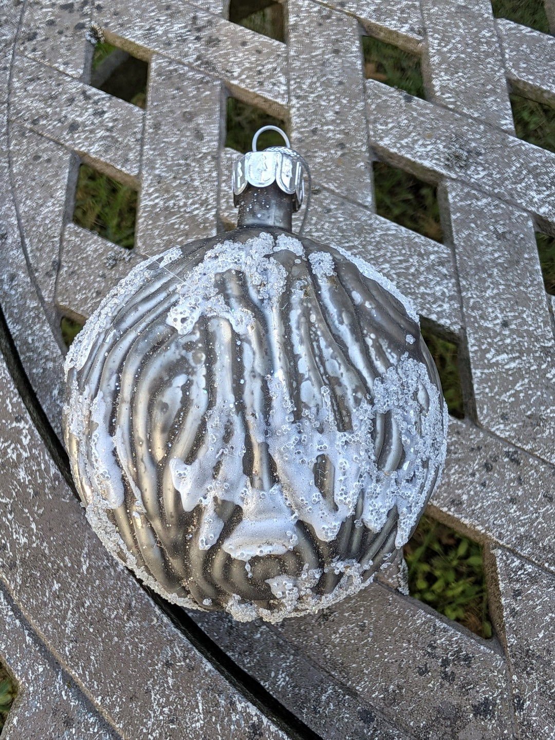 Weihnachtskugel mit Reliefstruktur und silberner Kappe mit Öse, schräg von oben fotografiert