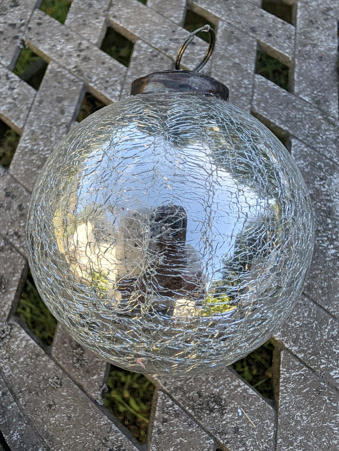 Silberne Christbaumkugel aus Glas mit Craquelé-Muster und Metallkappe mit goldfarbenem Aufhängering