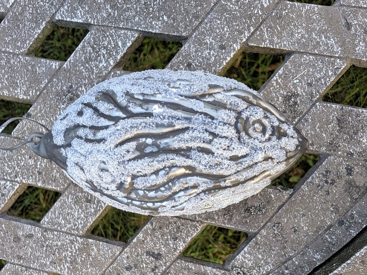 Grauer Baumschmuck in Tropfenform mit Aufhängeschlaufe, weiße Glitzerlinien auf glänzender Oberfläche