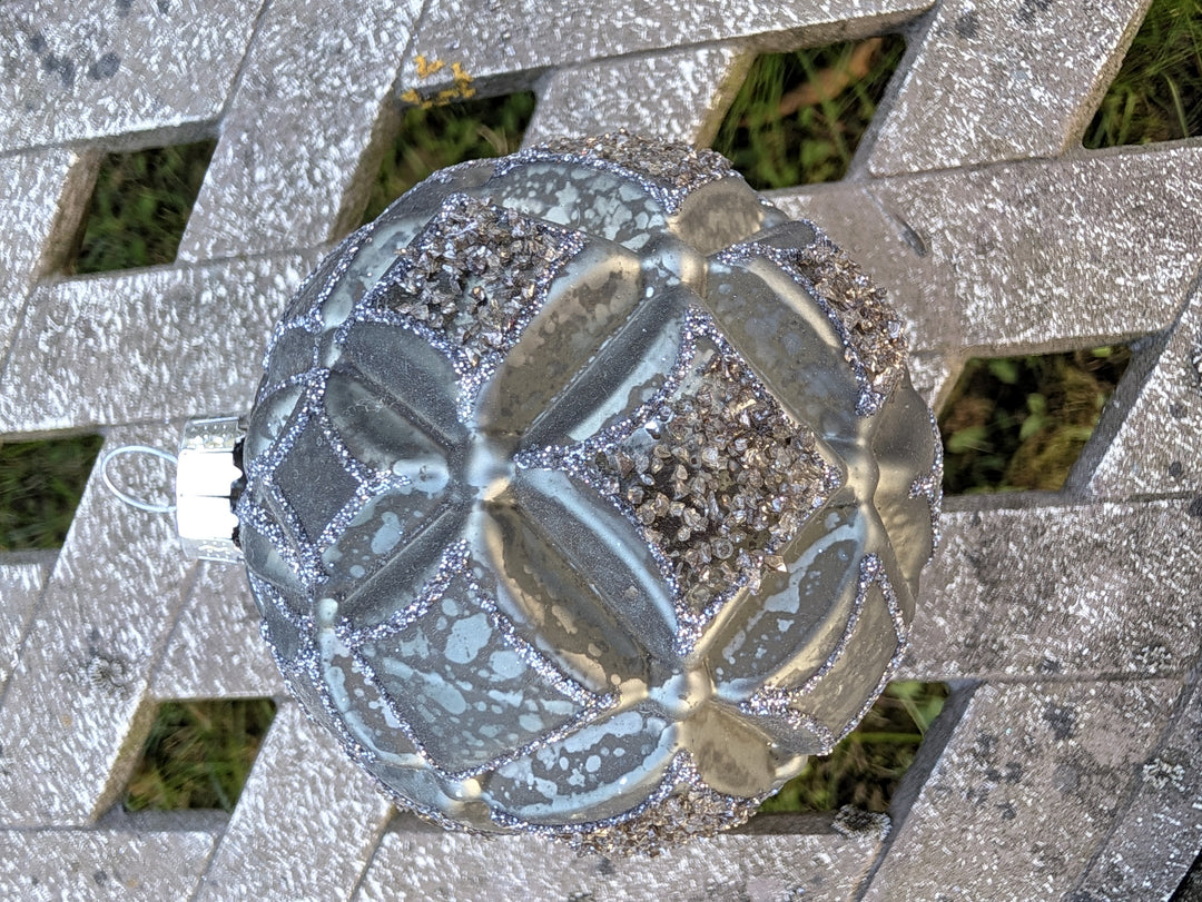 Christbaumkugel in Silber-Graugrün mit Rautenrelief, Glitzerlinien und Granulatfeldern, von oben fotografiert