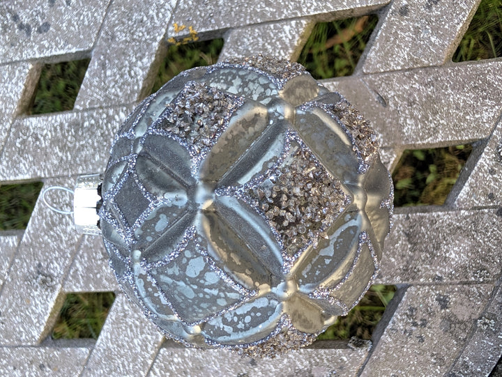 Christbaumkugel in Silber-Graugrün mit Rautenrelief, Glitzerlinien und Granulatfeldern, von oben fotografiert