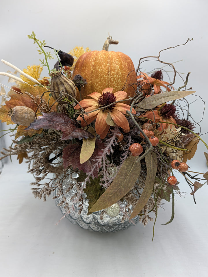 Herbstgesteck mit orangefarbenem Kürbis, Blüten, Beeren und Blättern in silbriger Schale, von oben gesehen