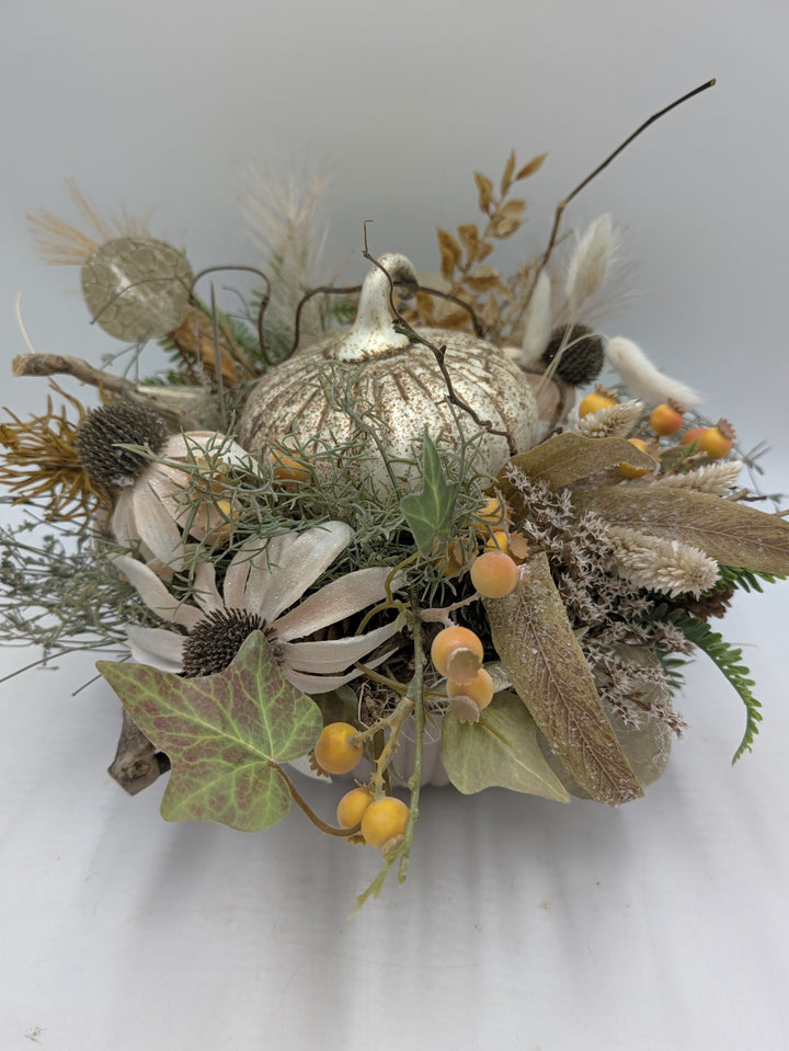 Herbstgesteck von oben: cremefarbener Kürbis, Sonnenhut, orange Beeren, Efeu und Gräser in Creme und Gold