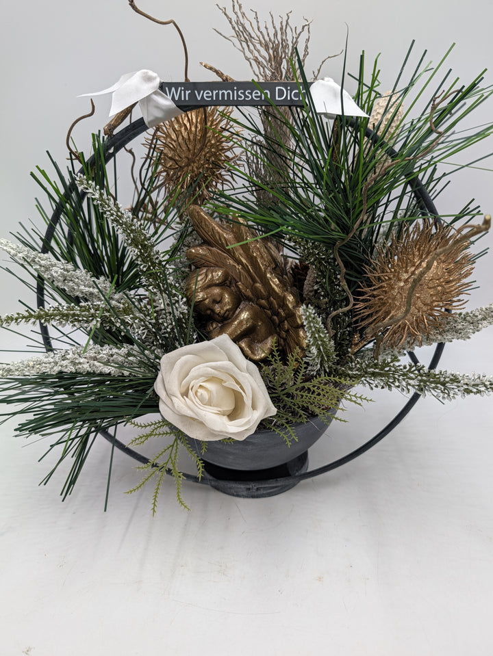 Grabgesteck in grauer Schale mit Metallring, goldenem Engel, weißer Rose, Kiefer, Heide und Schild "Wir vermissen Dich"