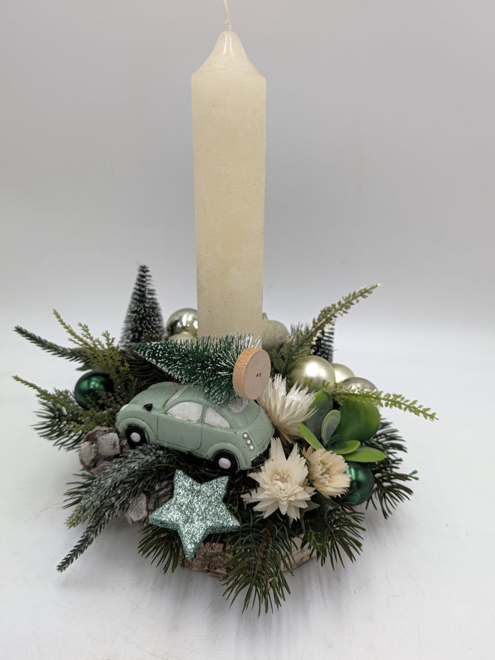 Weihnachtsgesteck mit cremefarbener Kerze, mintgrünem Auto mit Tannenbaum, Glitzerstern und Zapfen