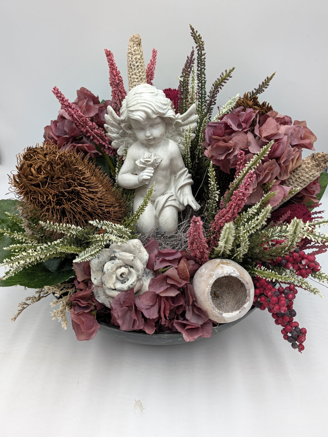 Trauergesteck von vorn: Engelfigur mit Rose, Hortensien in Altrosa, Banksia, Steinrose und Tongefäß