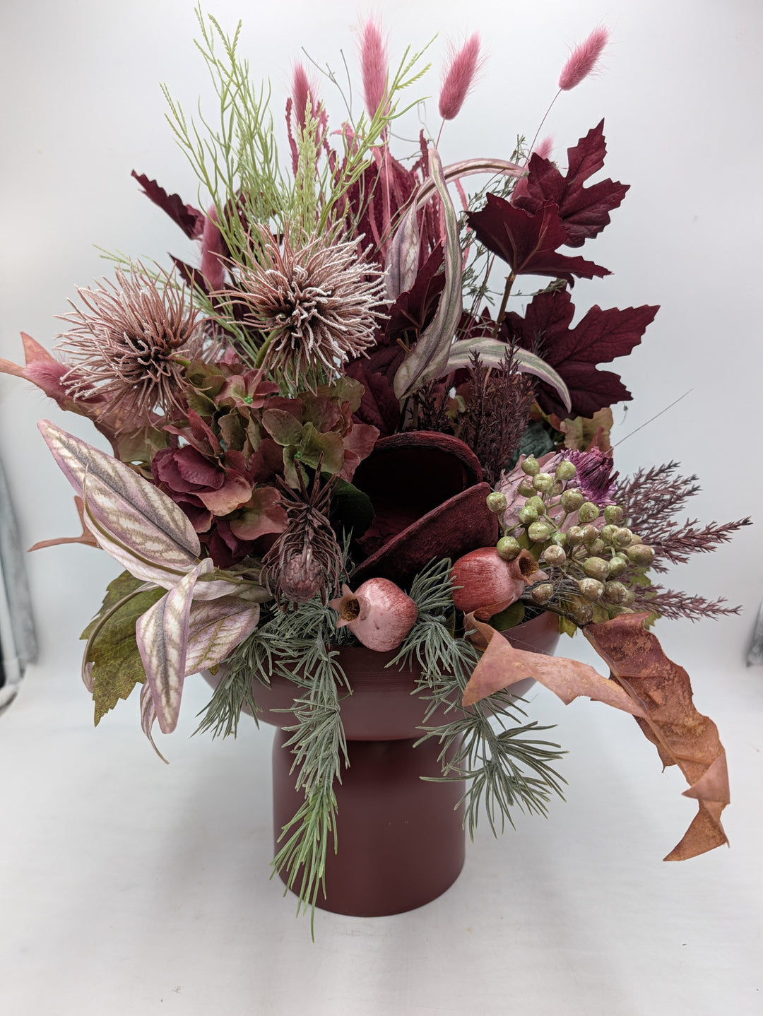 Herbstgesteck in Dunkelrot und Altrosa mit Hortensien, Disteln, Ahornblättern und rosa Gräsern in Keramikvase