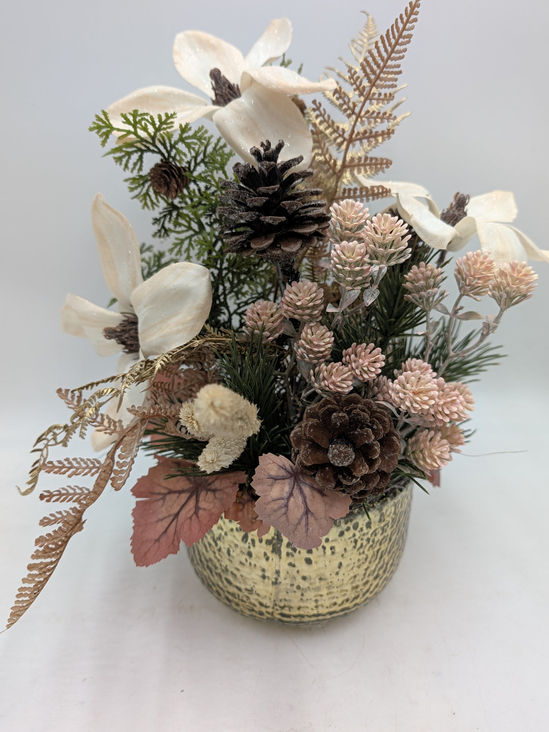 Nahansicht des Gestecks mit Magnolienblüten, goldbraunen Farnwedeln, Kiefernzweigen und rotbraunen Blättern