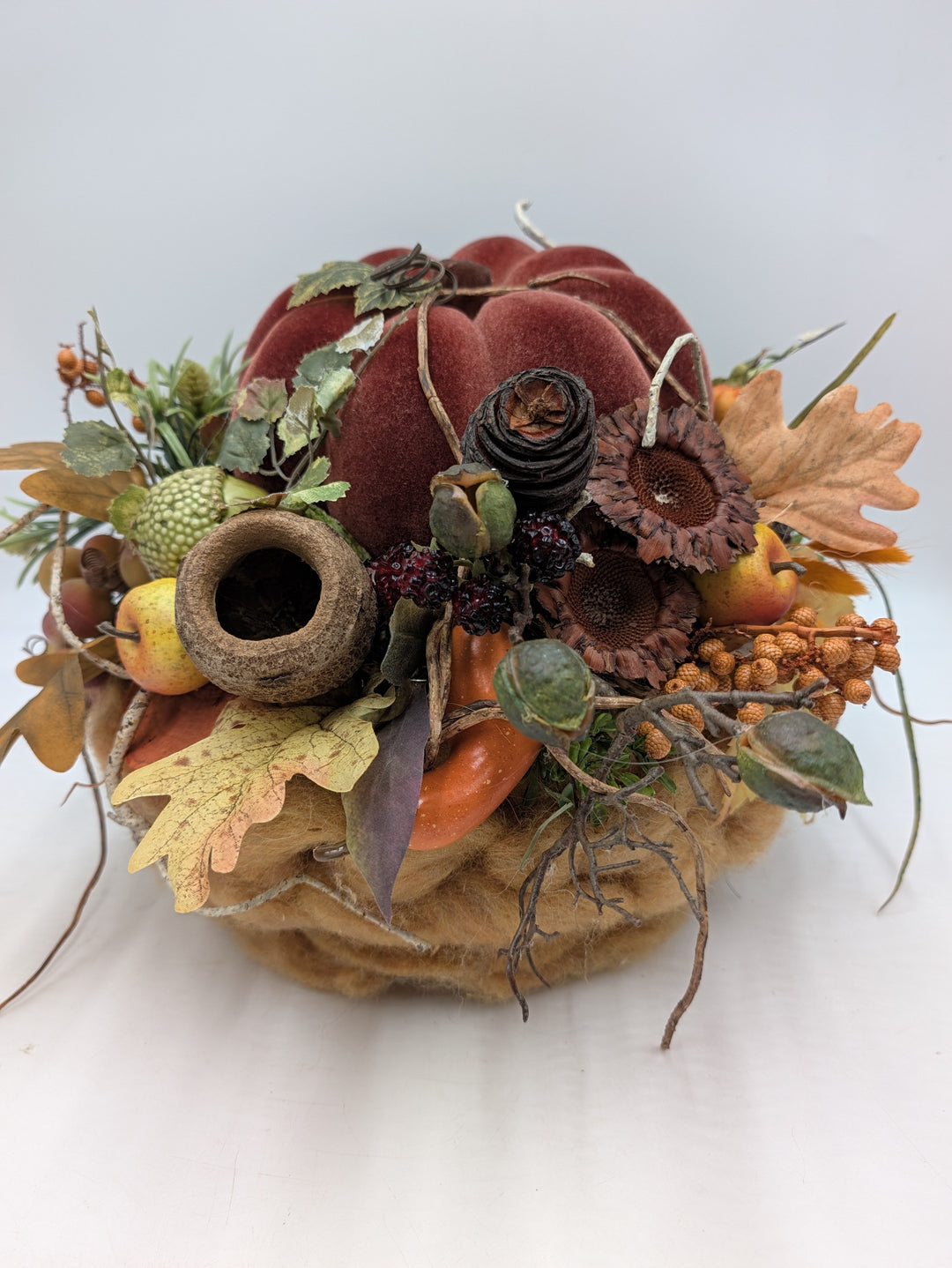 Herbstgesteck mit weinrotem Samtkürbis, getrockneten Sonnenblumen, Eicheln, Brombeeren und Herbstlaub