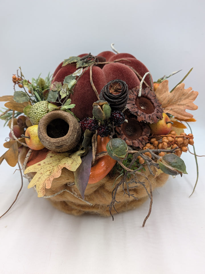 Herbstgesteck mit weinrotem Samtkürbis, getrockneten Sonnenblumen, Eicheln, Brombeeren und Herbstlaub