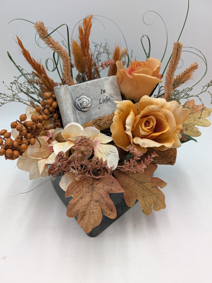 Trauergesteck mit orangen Rosen, cremefarbenen Hortensien, Gräsern und grauer Tafel mit Aufschrift In Liebe