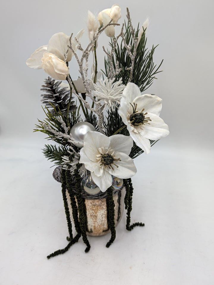 Seitliche Ansicht des Wintergestecks mit zwei weißen Christrosen, beschneiten Zweigen und hängenden grünen Rispen