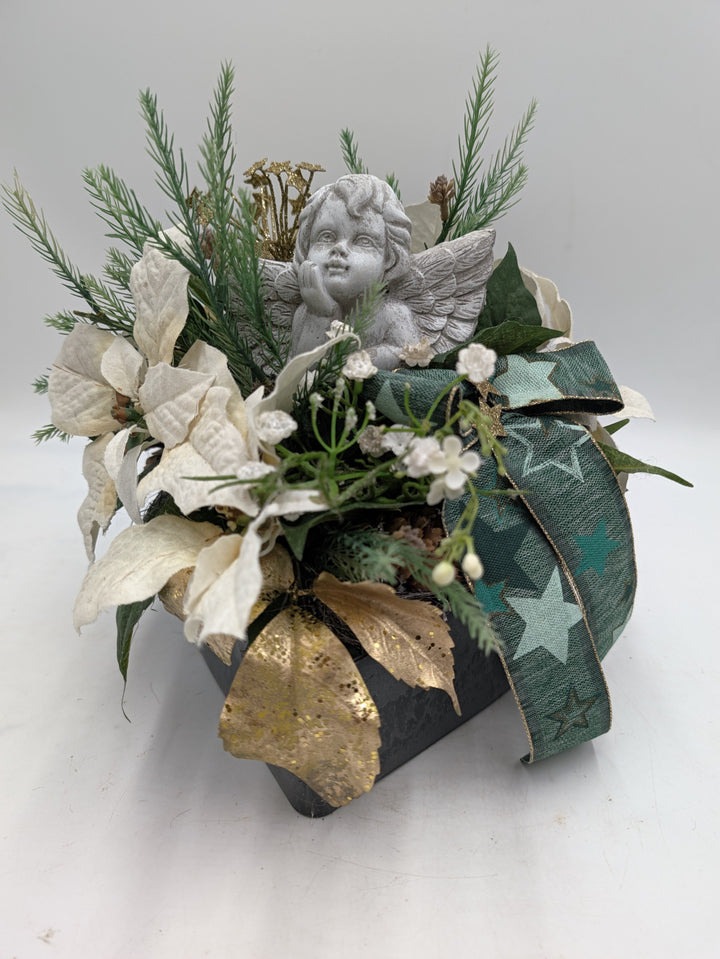 Winterliches Grabgesteck in schwarzem eckigem Gefäß mit Engelfigur, goldenen Glitzerblättern und weißen Beeren